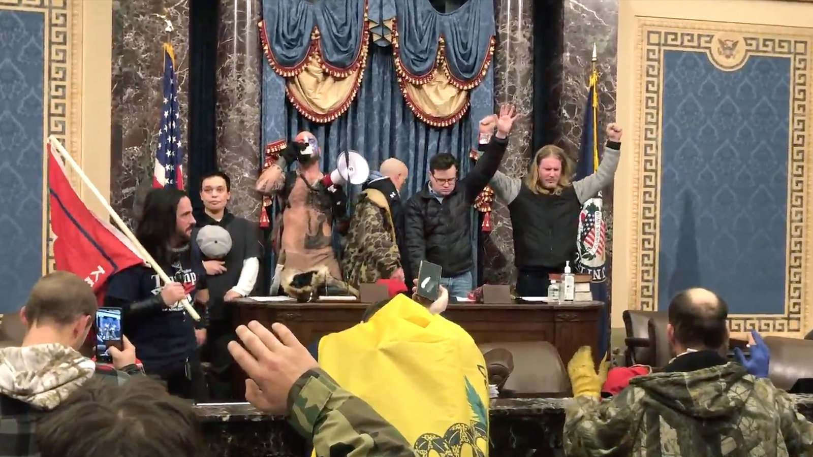 A group of insurrectionists pray inside the U.S. Senate chamber after breaching the Capitol, Jan. 6, 2021, in Washington. Video screengrab via Luke Mogelson/The New Yorker