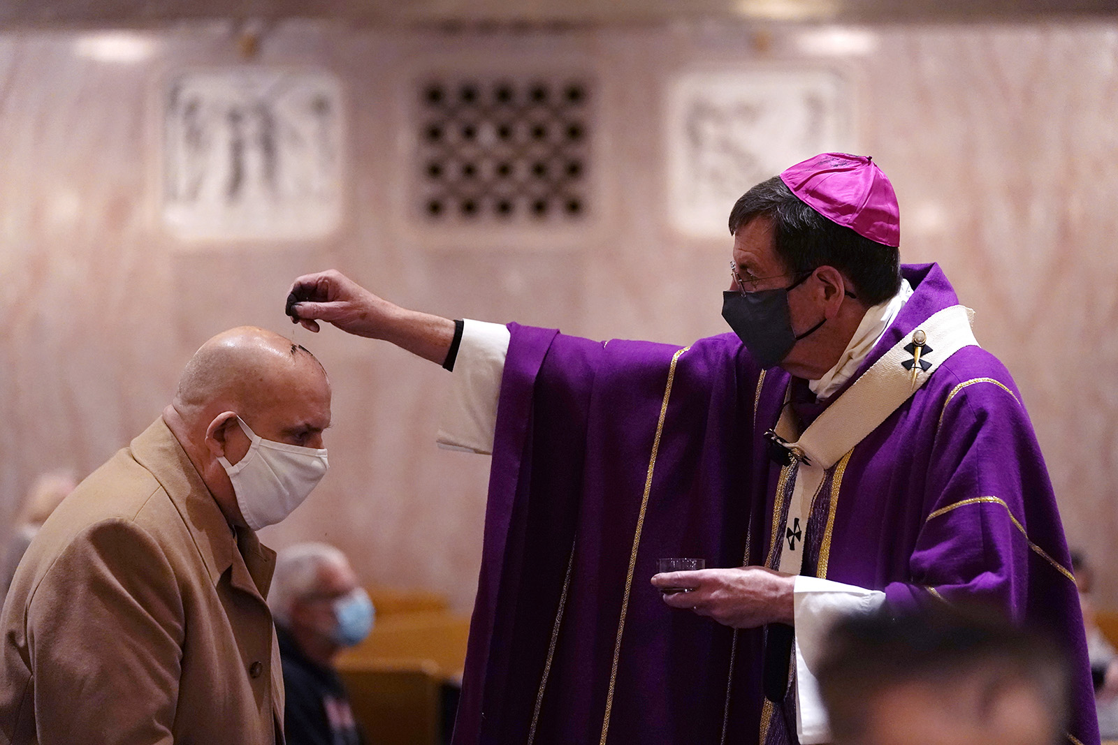 Archbishop of Detroit Allen H. Vigneron sprinkles ashes on Richard Lewandowski at the St. Aloysius Parish, Wednesday, Feb. 17, 2021, in Detroit. The ashes, a symbol of penance, are made from palm leaves used in last year's Palm Sunday liturgy. The sprinkling, because of the pandemic, is a departure from the usual practice of making the sign of the cross on the forehead and follows an ancient method still common in parts of the world today. (AP Photo/Carlos Osorio)