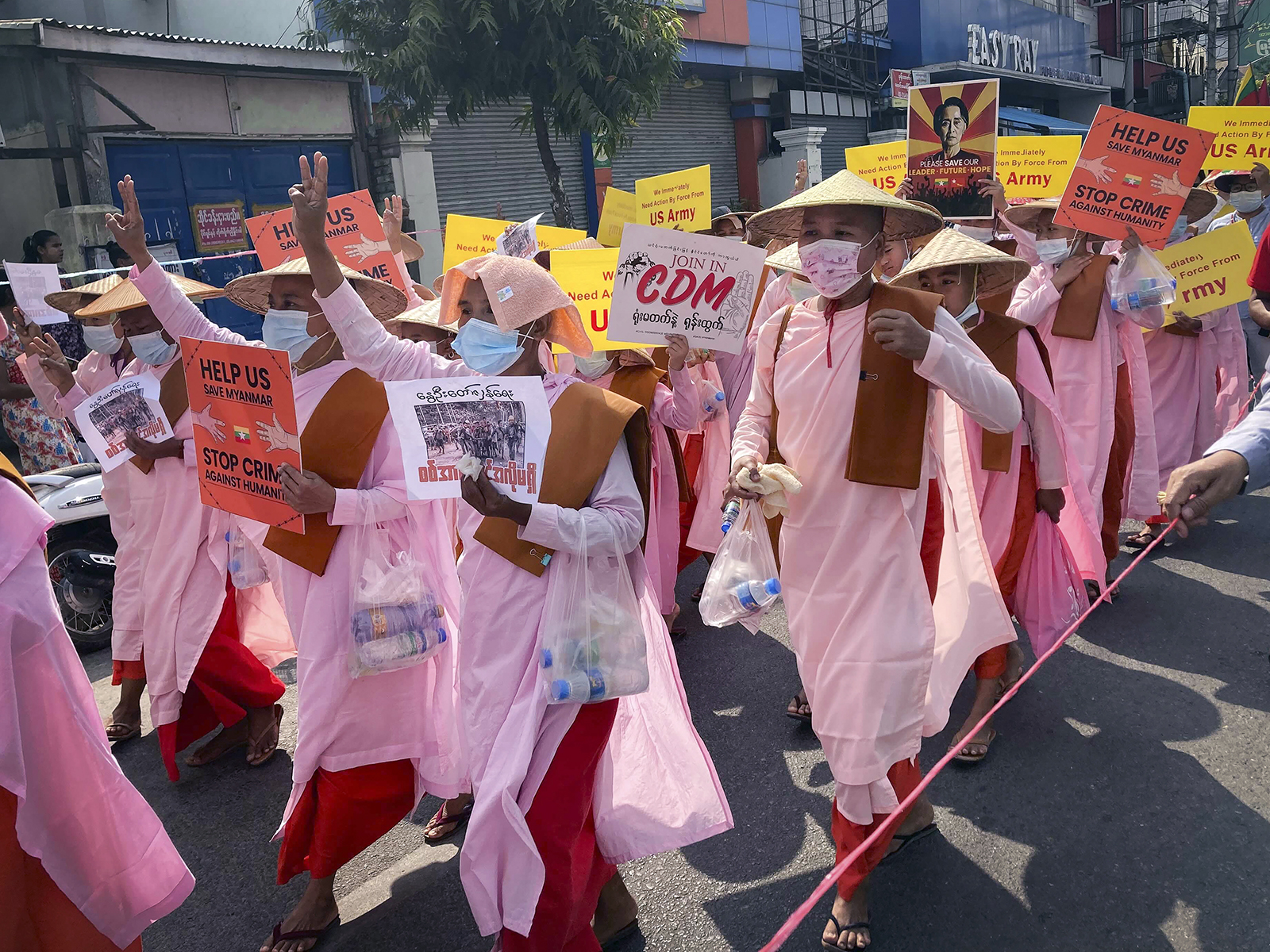 Buddhist nuns display signs, including images of deposed Myanmar leader Aung San Suu Kyi, during a street march in Mandalay, Myanmar, Friday, Feb. 26, 2021. Tensions escalated Thursday on the streets of Yangon, Myanmar's biggest city, as supporters of Myanmar's junta attacked people protesting the military government that took power in a coup, using slingshots, iron rods and knives to injure several of the demonstrators. (AP Photo)