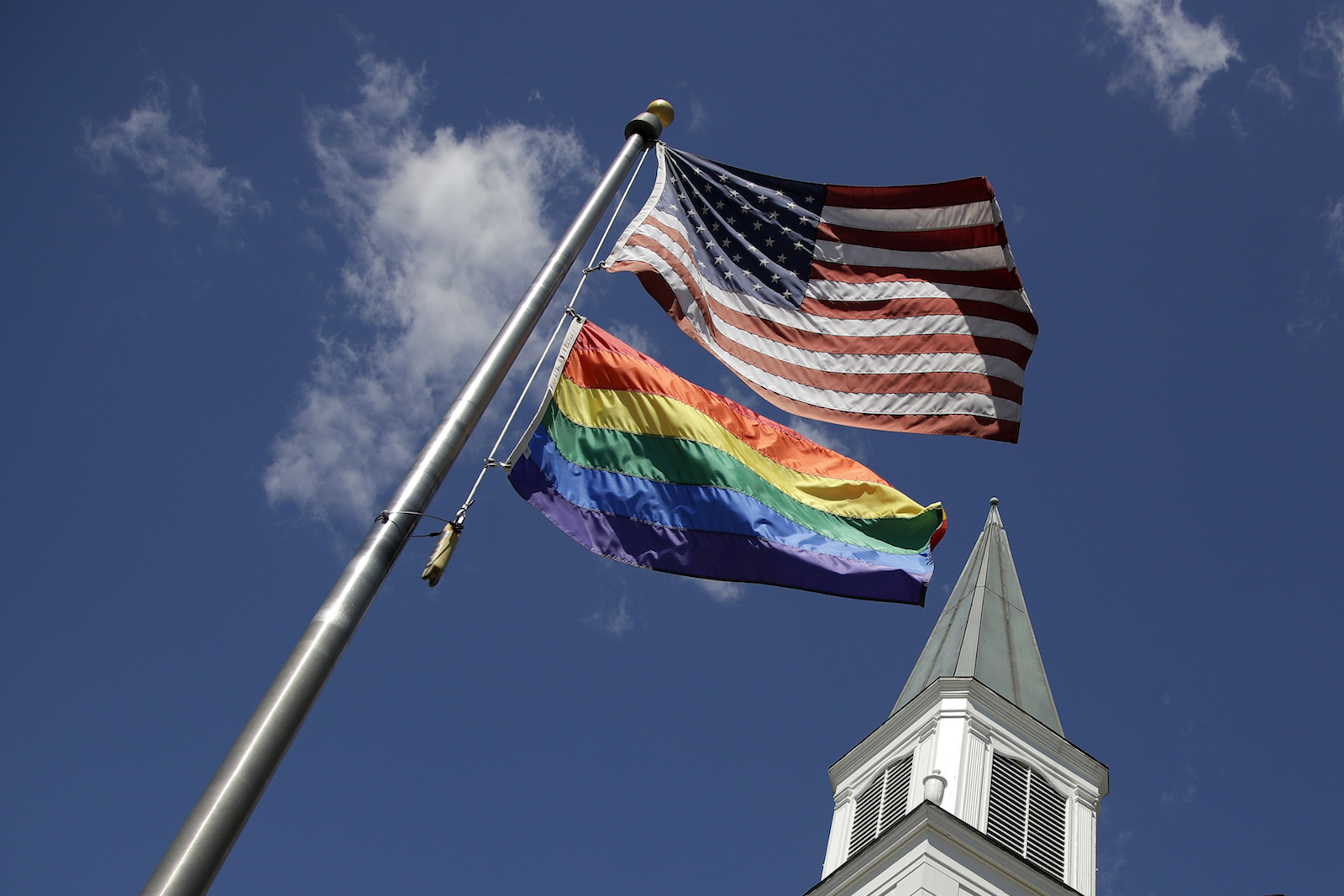 A gay pride flag flies along with the U.S. flag in front of a church in Prairie Village, Kansas, April 19, 2019. (AP Photo/Charlie Riedel)