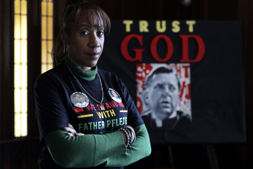 Activist Pam Bosley poses for a portrait infront of a portraiture of Father Michael Pfleger, inside the St. Sabina Catholic Church on Thursday, March 4, 2021, in Chicago. After the murder of her teenage son in 2006, Father Plfeger inspired her to become an activist, recruited her to run the South Side church's violence prevention office. (AP Photo/Shafkat Anowar)
