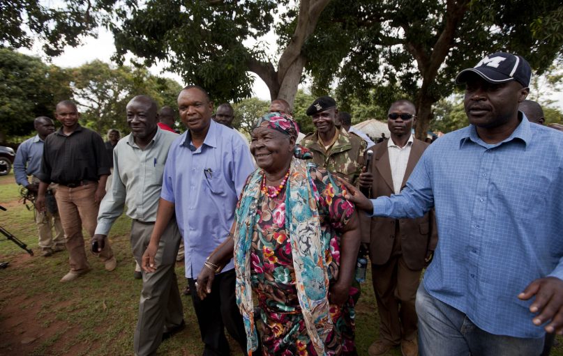 FILE - In this Tuesday, Nov. 6, 2012, file photo, Sarah Obama, center, step-grandmother of then U.S. President Barack Obama, walks back to her house after speaking to the media in the garden of her home in the village of Kogelo, western Kenya. Sarah Obama, the matriarch of Barack Obama's Kenyan family, has died, relatives and officials confirmed Monday, March 29, 2021 but did not disclose the cause of death. She was at least 99 years old. (AP Photo/Ben Curtis, File)