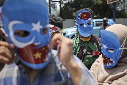 Muslim students wearing masks with the colors of the pro-independence East Turkistan flag attend a rally outside the Chinese Embassy in Jakarta, Indonesia, Thursday, March 25, 2021. About a dozen of students staged the rally calling to an end to alleged oppression against Muslim Uyghur ethnic minority in China's region of Xinjiang. (AP Photo/Dita Alangkara)