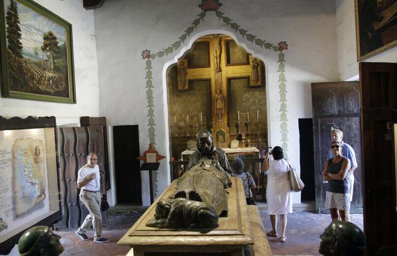 Visitors walk next to a sculpture paying homage to Junipero Serra at the Carmel Mission, Wednesday, Sept. 23, 2015, in Carmel-By-The-Sea, Calif. The 18th-century missionary who brought Catholicism to the American West Coast was elevated to sainthood by Pope Francis in the first canonization on U.S. soil. (AP Photo/Marcio Jose Sanchez)