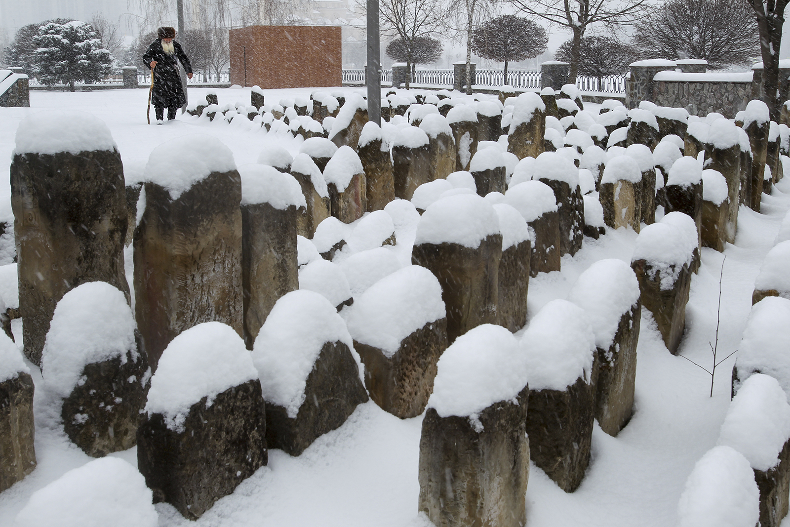 An elderly Chechen man walks to pray at a snow-covered cemetery, a memorial to the Stalin-era deportation's victims, in Grozny, Russia, Friday, March 12, 2021. Chechens and Ingush were victims of the 1944 deportations to the barren steppes of then-Soviet Central Asia. (AP Photo/Musa Sadulayev)