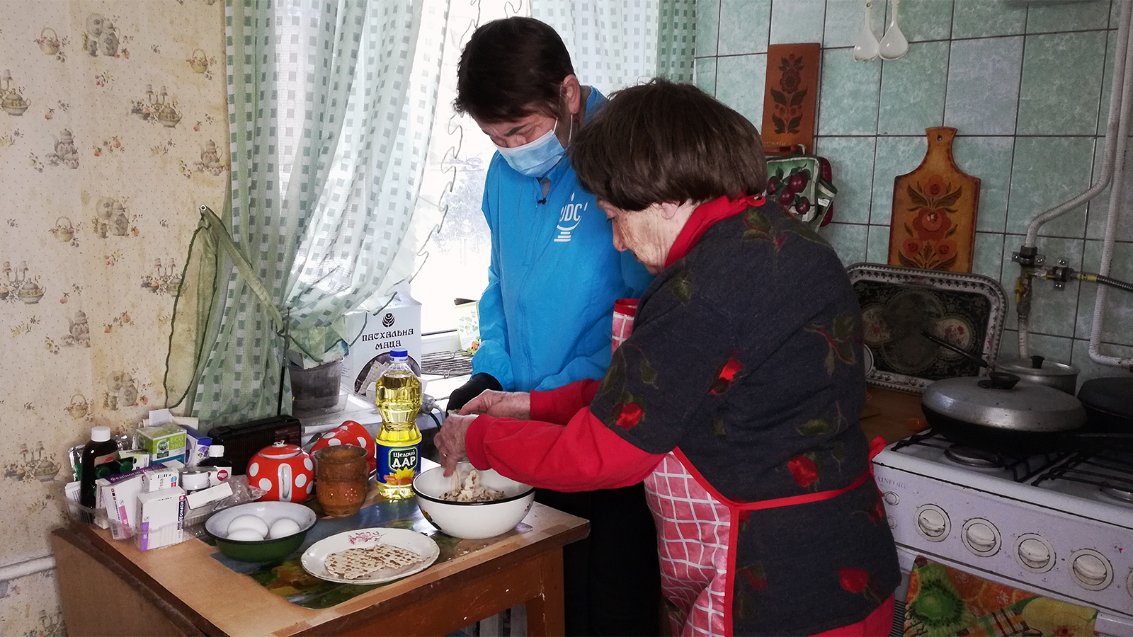 Nina Belitskaya, right, teaches a local Jewish volunteer who delivered a matzah box how to make matzah brei, a fried egg/matzah dish very popular among Ashkenazi Jews on Passover, in 2021. Photo courtesy of JDC