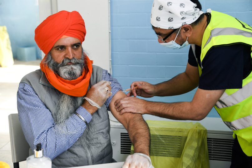 Dr Manraj Barhey administers a dose of AstraZeneca COVID-19 vaccine to Mr Baltjit Singh, President of the Luton Guru Nanak Gurdwara Sikh temple in Luton, Bedfordshire, as the world’s first Vaisakhi Vaccine Clinic is launched today, Sunday, March 21, 2021.(AP Photo/Alberto Pezzali)