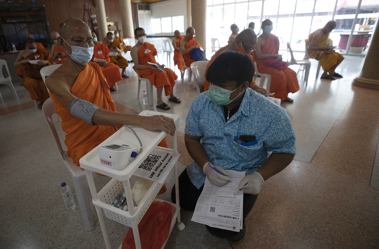 A health worker checks blood pressure of a Buddhist monk who received AstraZeneca COVID-19 vaccine for side effects at Nak Prok Temple in Bangkok, Thailand, Friday, April 9, 2021. (AP Photo/Sakchai Lalit)