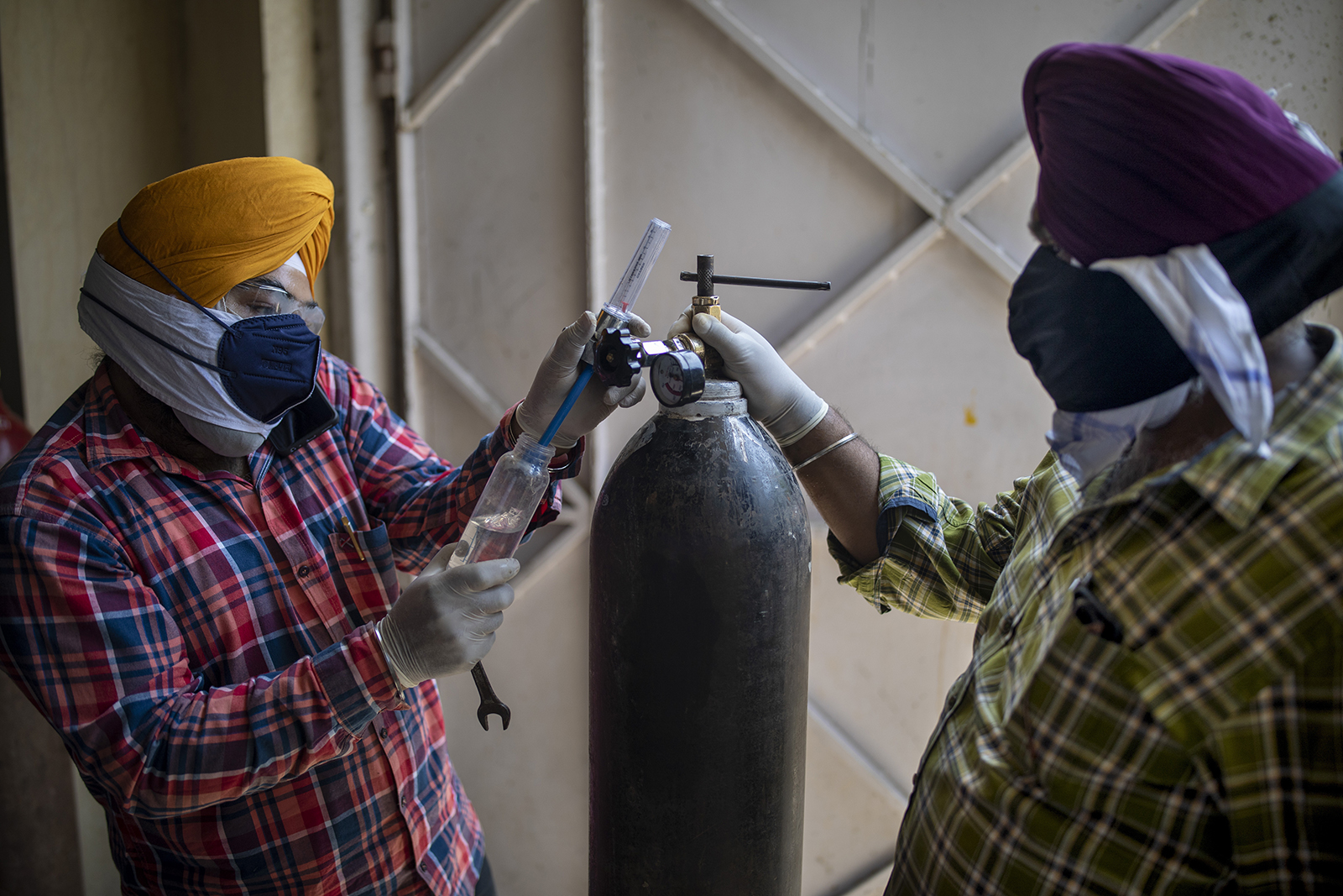Volunteers from a Gurdwara, a Sikh house of worship, prepare oxygen cylinders for patients in New Delhi, India, Saturday, April 24, 2021. India’s medical oxygen shortage has become so dire that this gurdwara began offering free breathing sessions with shared tanks to COVID-19 patients waiting for a hospital bed. They arrive in their cars, on foot or in three-wheeled taxis, desperate for a mask and tube attached to the precious oxygen tanks outside the gurdwara in a neighborhood outside New Delhi. (AP Photo/Altaf Qadri)