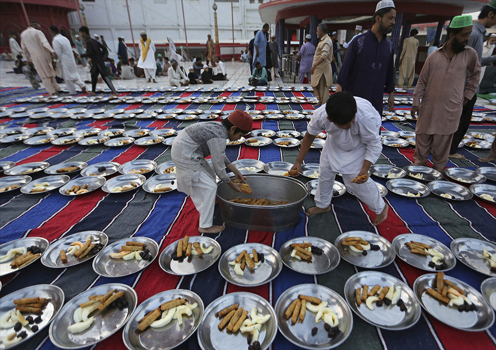 Volunteers prepare food plates to be distributed to people for breaking their fast during the Muslim holy fasting month of Ramadan, at a mosque in Karachi, Pakistan, Wednesday, April 14, 2021. Ramadan is marked by daily fasting from dawn to sunset. (AP Photo/Fareed Khan)