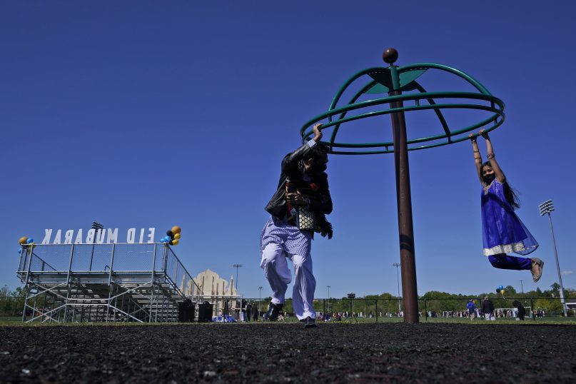 Saif Chaudhry plays with his daughter Ariana Chaudhry, 8, on a playground near the site of an outdoor celebration of Eid al-Fitr in Overpeck County Park in Ridgefield Park, New Jersey, May 13, 2021, at the end of Ramadan. (AP Photo/Seth Wenig)
