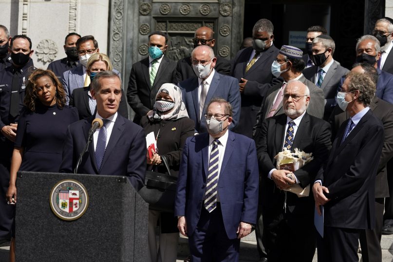 FILE - In this Thursday, May 20, 2021, file photo, Los Angeles Mayor Eric Garcetti, at podium, speaks in front of civic and faith leaders outside City Hall in Los Angeles. Faith and community leaders in Los Angeles called for peace, tolerance and unity in the wake of violence in the city that is being investigated as potential hate crimes. Los Angeles police on Saturday, May 22, 2021 announced the arrest of a suspect in an alleged attack by a pro-Palestinian group on Jewish men outside a restaurant earlier in the week. (AP Photo/Marcio Jose Sanchez, File)