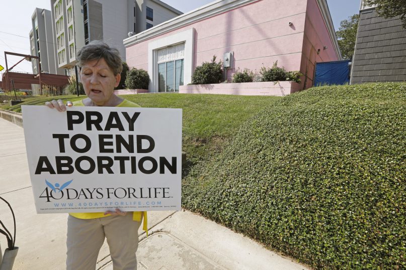 FILE - In this Oct. 2, 2019. file photo, an abortion opponent sings to herself outside the Jackson Womens Health Organization clinic in Jackson, Miss. The Supreme Court has agreed to hear a potentially ground-breaking abortion case, and the news is energizing activists on both sides of the contentious issue. They're already girding to make abortion access a high-profile issue in next year’s midterm elections. (AP Photo/Rogelio V. Solis, File)