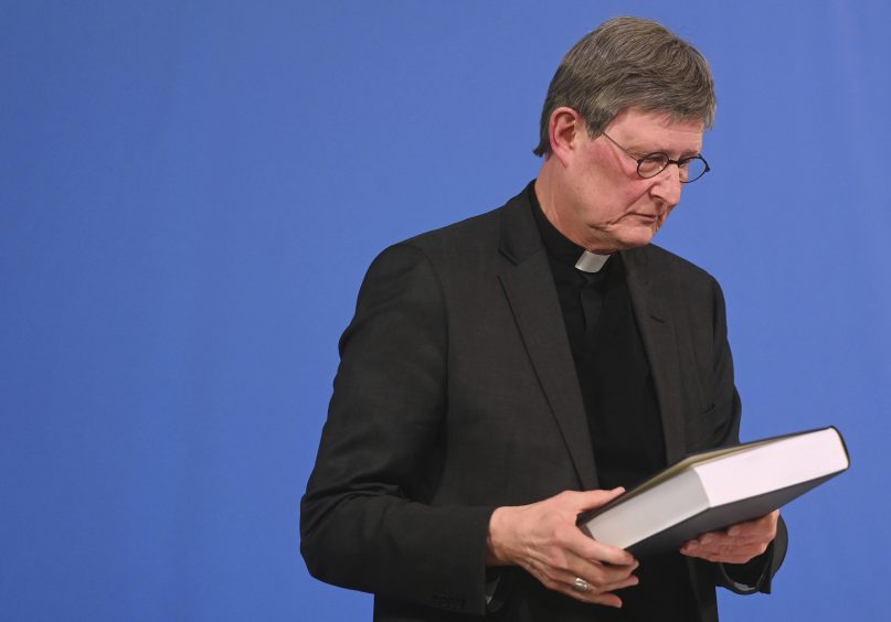 In this March 18, 2021, file photo, Cardinal Rainer Maria Woelki holds a report on abuse by clergy he had receives during a news conference in Cologne, Germany. Pope Francis is sending envoys to the German Archdiocese of Cologne to look into possible mistakes by church officials in handling past sexual abuse cases and the “complex pastoral situation” in the deeply divided church there. (Ina Fassbender/Pool via AP, file)