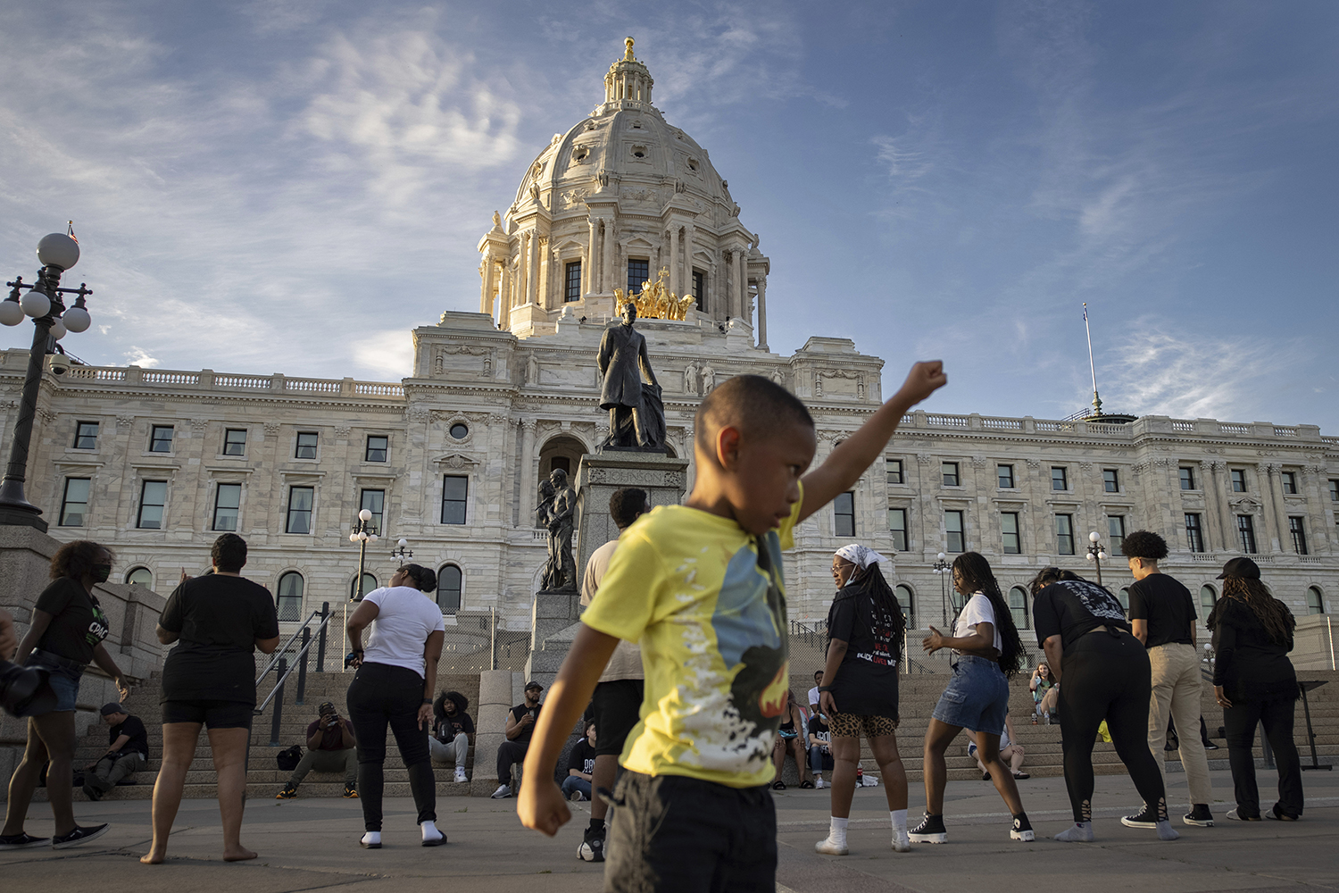 A young boy holds his fist up as people dance at a rally and march May 24, 2021, in St. Paul, Minnesota, organized by families who were victims of police brutality. The event marked the one-year anniversary of George Floyd's death. (AP Photo/Christian Monterrosa)