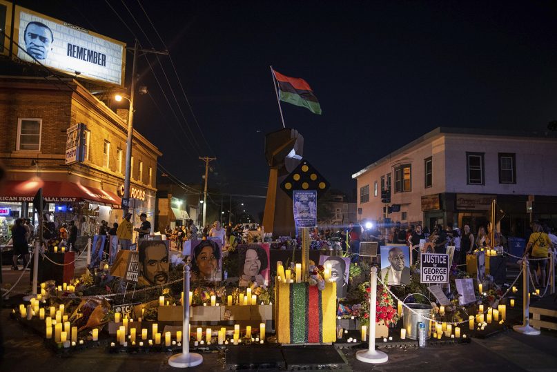 Community members place candles around the iron fist at 38th Street and Chicago Avenue--informally known as George Floyd Square--on the one-year anniversary of George Floyd's death, Tuesday, May 25, 2021, in Minneapolis. (AP Photo/Christian Monterrosa)