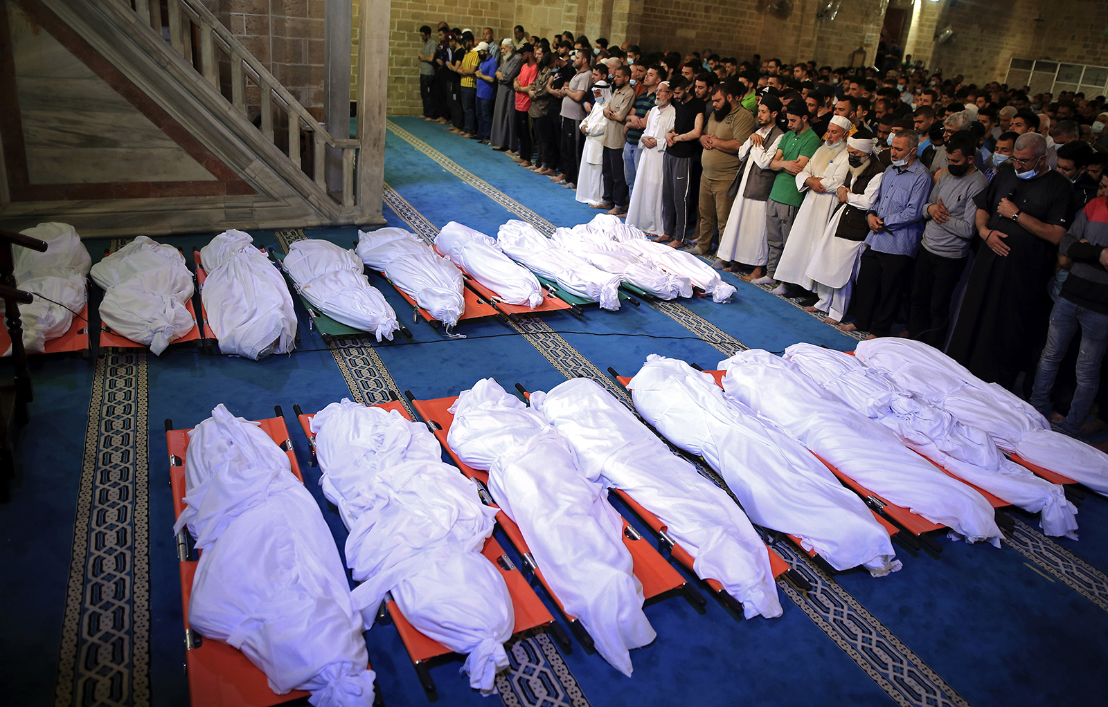 Mourners pray over the bodies of 17 Palestinians who were killed in overnight Israeli airstrikes in Gaza City, Sunday, May 16, 2021. (AP Photo/Sanad Latifa)