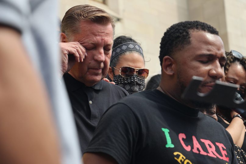 Supporters pray for the Rev. Michael Pfleger as he wipes his eye on May 24, 2021, outside his church, the Faith Community of St. Sabina in Chicago's Auburn-Gresham neighborhood. RNS photo by Emily McFarlan Miller