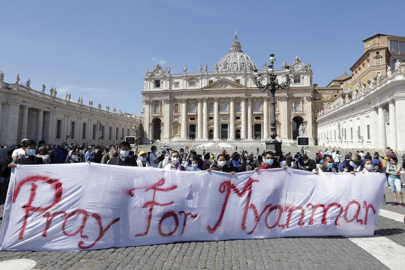 Nuns and priests hold up a banner reading 