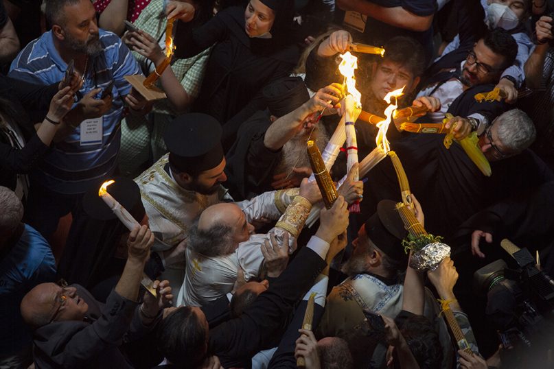 Greek Orthodox Patriarch of Jerusalem Theophilos III, center left, holds candles for Christian pilgrims during the ceremony of the Holy Fire at the Church of the Holy Sepulchre, in the Old City of Jerusalem, May 1, 2021. (AP Photo/Ariel Schalit)