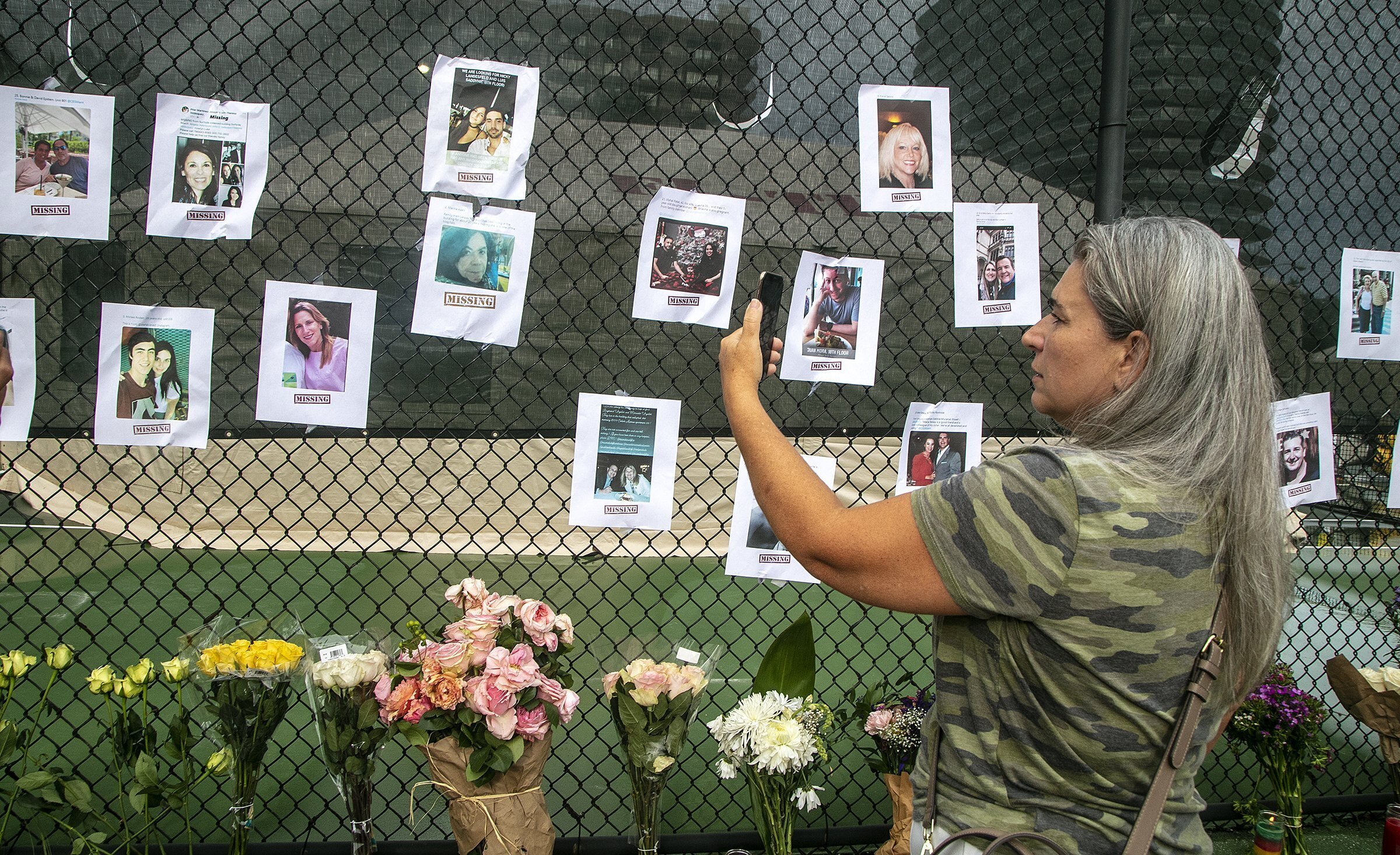 Photos of missing people are posted on a fence near the site of the Champlain Towers South Condo after the building collapsed Friday, June 25, 2021 in Surfside, Fla. The apartment building partially collapsed on Thursday, June 24. (Pedro Portal/Miami Herald via AP)