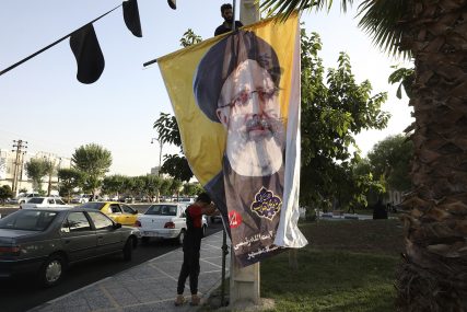 Two workers hang a banner of the presidential candidate Ebrahim Raisi, currently judiciary chief, near his campaign rally in town of Eslamshahr southwest of the capital Tehran, Iran, Sunday, June 6, 2021. Iran will hold presidential elections on June 18 with 7 candidates approved by the Guardian Council. (AP Photo/Vahid Salemi)