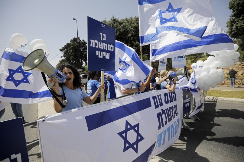 Israeli protesters hold flags and chant slogans during a demonstration in support of the new government, outside the Knesset, Israel's parliament, in Jerusalem, Sunday, June 13, 2021. (AP Photo/Sebastian Scheiner)