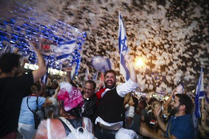 Israelis celebrate the swearing in of the new government in Tel Aviv, Israel, Sunday, June 13, 2021. Israel's parliament has voted in favor of a new coalition government, formally ending Prime Minister Benjamin Netanyahu's historic 12-year rule. Naftali Bennett, a former ally of Netanyahu became the new prime minister. (AP Photo/Oded Balilty)