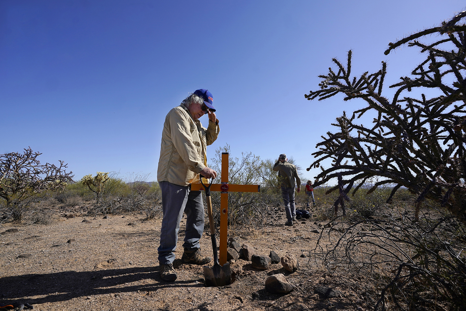 Alvaro Enciso, part of the Tucson Samaritans volunteer group, pauses as he and a group of other volunteers place a new cross at the site of the migrant who died in the desert some time ago, on Tuesday, May 18, 2021, in the desert near Three Points, Ariz. Enciso says he plants three or four crosses each week. “Can you imagine what their families go through, not knowing what happened to them?” (AP Photo/Ross D. Franklin)