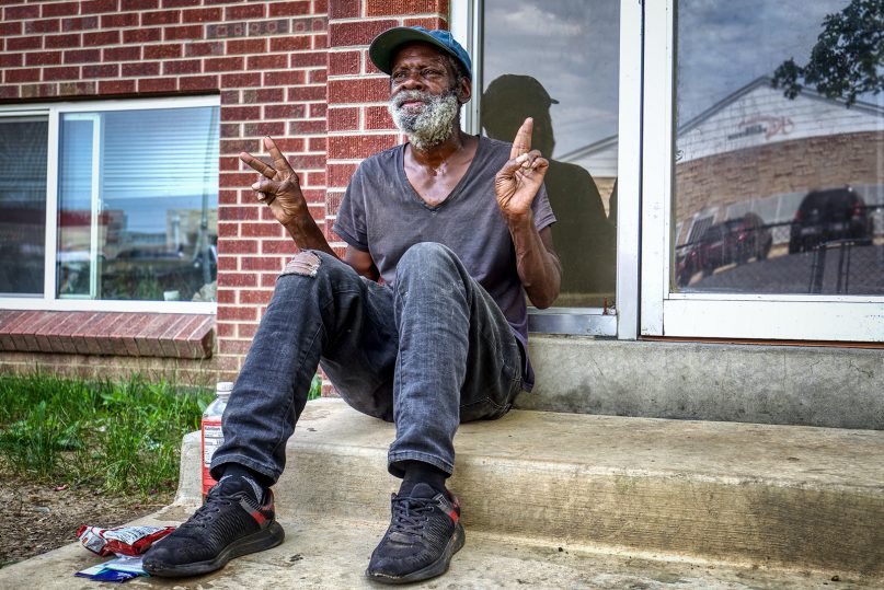 An elderly man sits outside an apartment building in Aurora, Colorado, in 2021. Photo by Andrew Coop/Unsplash/Creative Commons