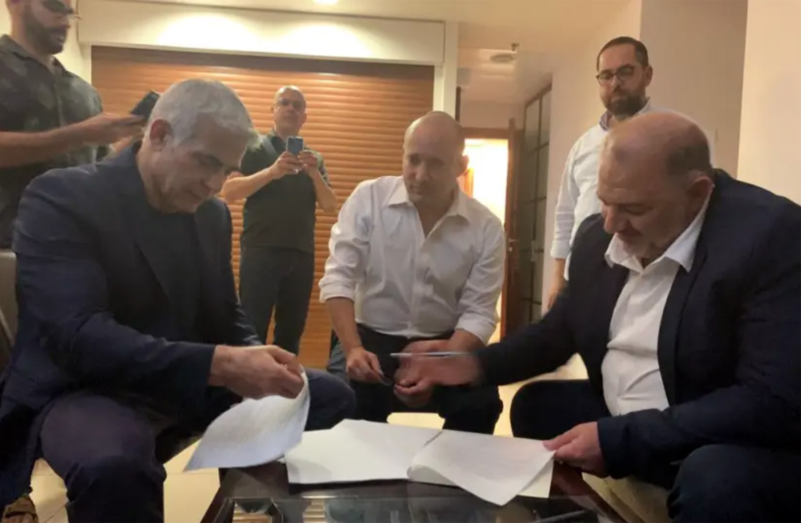 Yair Lapid, from left, Naftali Bennett, and Mansour Abbas are seen signing a coalition deal. (Photo credit: RA'AM, via social media)
