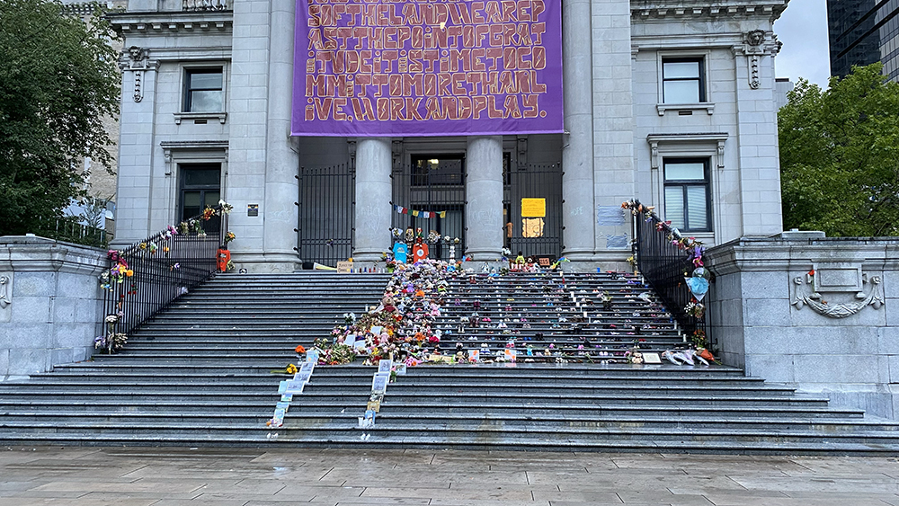 A community memorial on the steps of the Vancouver Art Gallery on June 6, 2021, for the 215 children discovered buried outside Kamloops Indian Residential School. The main memorial consists of 215 pairs of children’s shoes, along with various accessories including teddy bears, books, images, and flowers. Photo by Frozemint/Creative Commons
