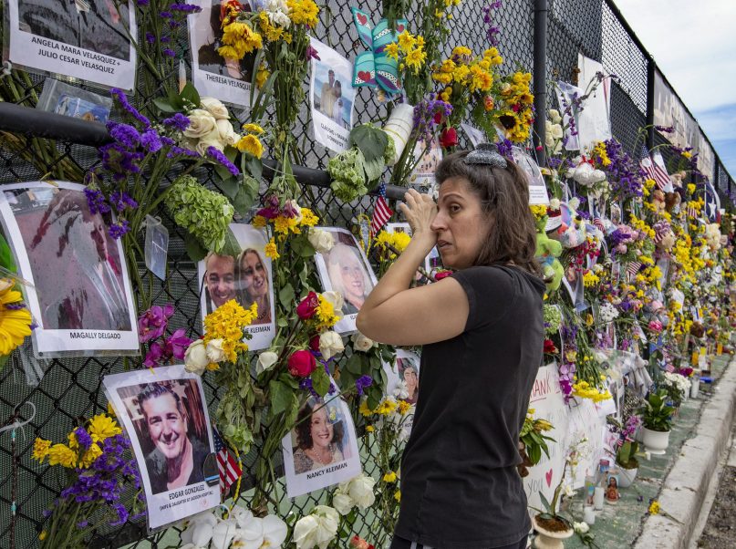 Gini Gonte visits the Surfside Wall of Hope & Memorial on Wednesday, July 7, 2021, as she honors her friends Nancy Kress Levin and Jay Kleiman, who lost their lives after the collapse of the Champlain Towers South in Surfside, Fla. (Al Diaz/Miami Herald via AP)