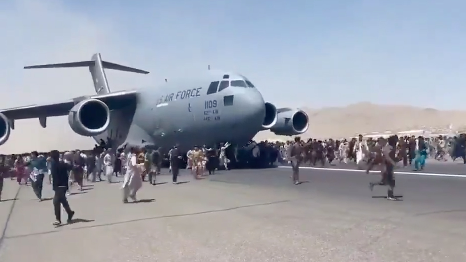 Hundreds of people run alongside a U.S. Air Force C-17 transport plane as it moves down a runway of the international airport, in Kabul, Afghanistan, Aug. 16, 2021. Thousands of Afghans rushed onto the tarmac at the airport, attempting to flee the Taliban. Video screengrab via Twitter/@Mukhtarwafayee