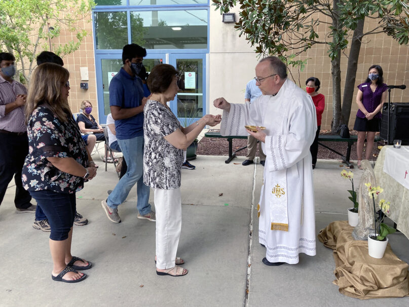 The Rev. Dan Oschwald administers Holy Communion to congregants during a Mass for Mother Teresa Catholic Church, held at Green Hope High School, in Cary, North Carolina, Sunday, Aug. 15, 2021. RNS photo by Yonat Shimron