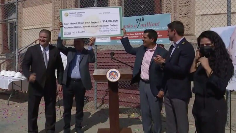 From left, California state Sen. Bob Hertzberg;  Stephen Sass, founding president of the Breed Street Shul Project; state Assemblyman Miguel Santiago; state Assemblyman Jesse Gabriel; and Brenda Hernández, executive director of the Weingart East Los Angeles YMCA, cheer after announcing $14.9 million in funding to renovate the century-old Breed Street Shul in the Boyle Heights neighborhood of Los Angeles, Aug. 10, 2021. Video screen grab