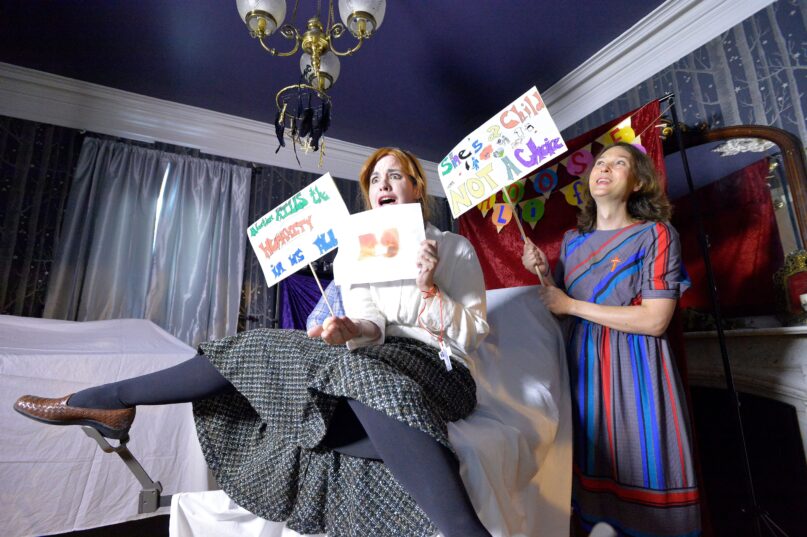 Two women hold mock pro-life signs in what they call an 'Abortrait room' at the Satanic Temple’s headquarters to protest abortion laws.
 (Joseph Prezioso / AFP via Getty images)