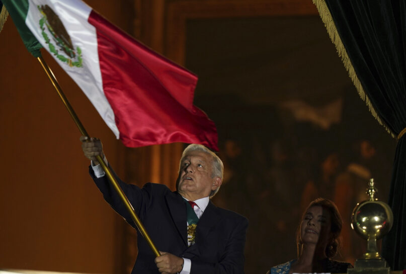 Mexican President Andres Manuel Lopez Obrador waves the national flag after giving the annual independence shout from the balcony of the National Palace to kick off subdued Independence Day celebrations amid the ongoing coronavirus pandemic, at the Zocalo in Mexico City, Wednesday, Sept. 15, 2021. (AP Photo/Fernando Llano)