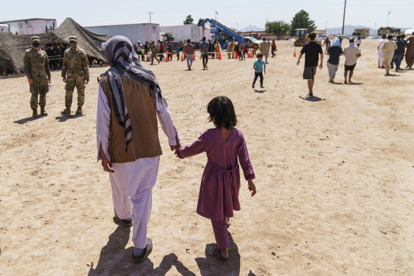 A man walks with a child through the Doña Ana Village of Fort Bliss, where Afghan refugees are being housed, in New Mexico, Sept. 10, 2021. The Biden administration provided the first public look inside the U.S. military base where Afghans airlifted out of Afghanistan are screened, amid questions about how the government is caring for the refugees and vetting them. (AP Photo/David Goldman)