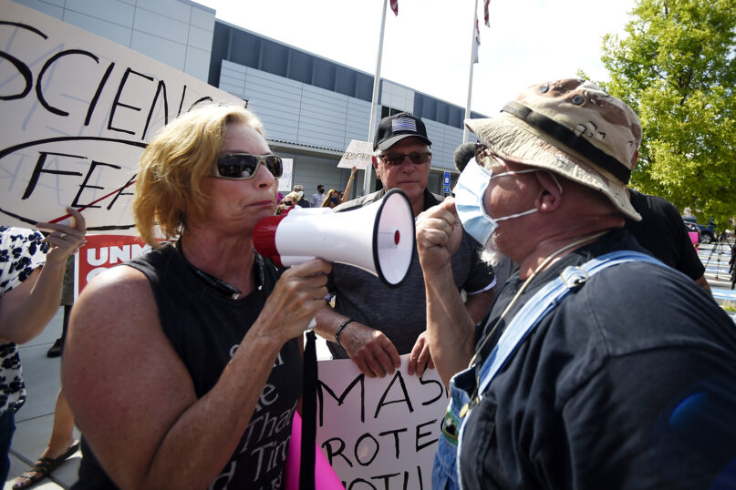 A pro-mask demonstrator, right, speaks with a non-mask demonstrator, left at the Cobb County School Board Headquarters during a pro-mask-wearing protest, Thursday, Aug. 12, 2021, in Marietta, Ga. Many school districts nationwide have seen parents protesting for and against masks. (AP Photo/Mike Stewart)