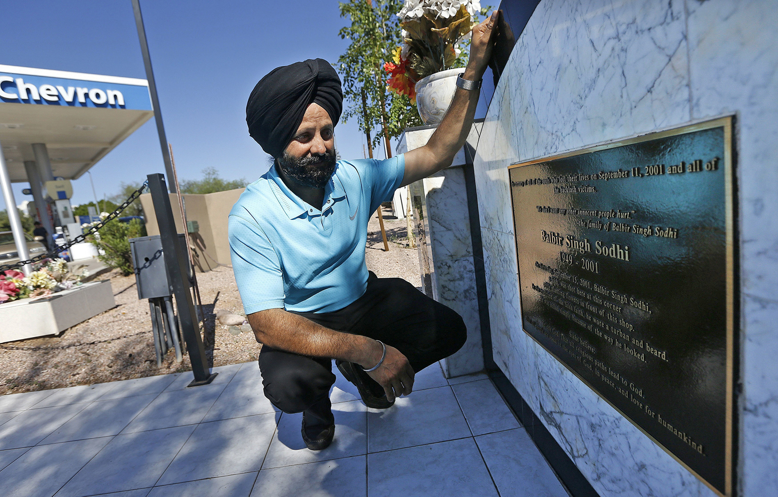 FILE - In this Aug. 19, 2016 file photo, Rana Singh Sodhi, kneels near his service station in Mesa, Ariz., next to a memorial for his brother, Balbir Singh Sodhi, who was murdered in the days after the Sept. 11 terrorist attacks. Sodhi, a Sikh American was killed at his Arizona gas station four days following the Sept. 11 attacks by a man who announced he was "going to go out and shoot some towel-heads" and mistook him for an Arab Muslim. (AP Photo/Ross D. Franklin, File)
