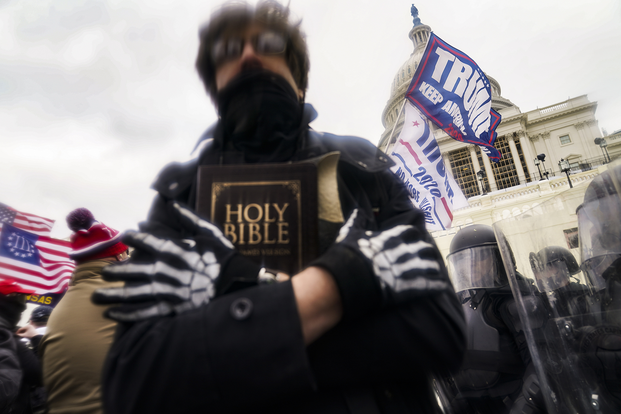 FILE - In this Wednesday, Jan. 6, 2021 file photo, a man holds a Bible as Trump supporters gather outside the Capitol in Washington. The Christian imagery and rhetoric on view during this month’s Capitol insurrection are sparking renewed debate about the societal effects of melding Christian faith with an exclusionary breed of nationalism. (AP Photo/John Minchillo)