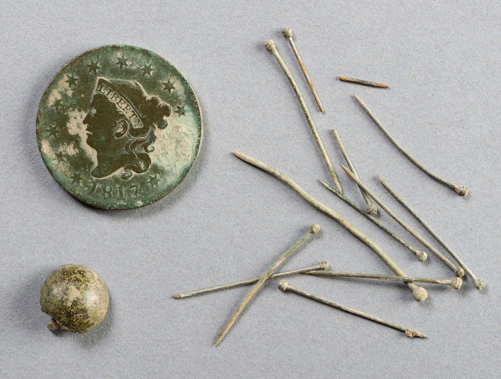 A One Cent coin, button and pins from the First Baptist Church archaeological site in Williamsburg, Virginia. Photo courtesy of Colonial Williamsburg Foundation