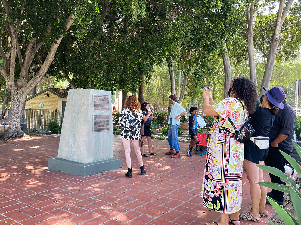 A group of people view the virtual monument through an app at the site where the Junipero Serra statue used to stand before it was toppled last July. RNS Photo by Alejandra Molina