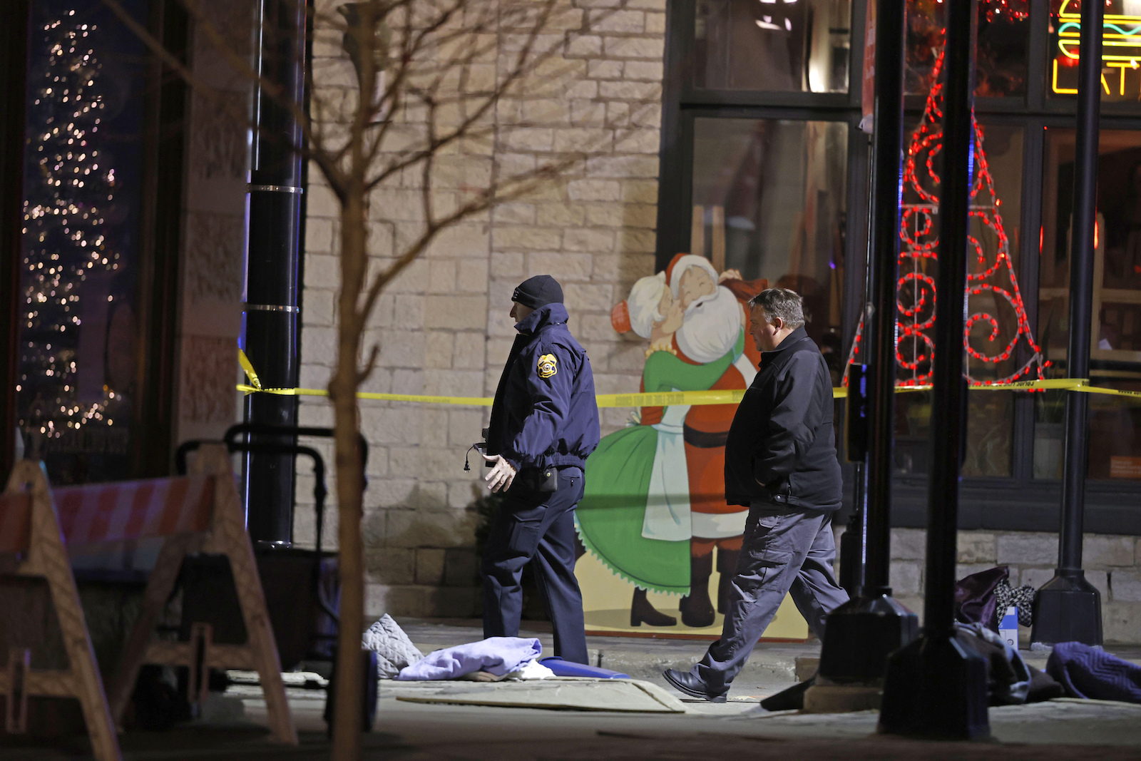 Holiday decorations frame police investigators in downtown Waukesha, Wisconsin, after a vehicle plowed into a Christmas parade, killing five people and injuring dozens of others, Nov. 21, 2021. (AP Photo Jeffrey Phelps)