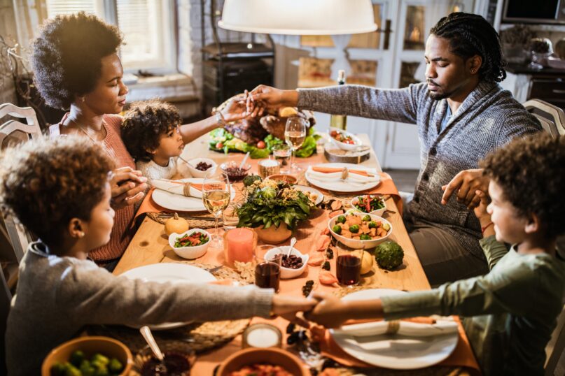 A family holds hands and prays before a Thanksgiving meal. ( skynesher/E+ via Getty Images)