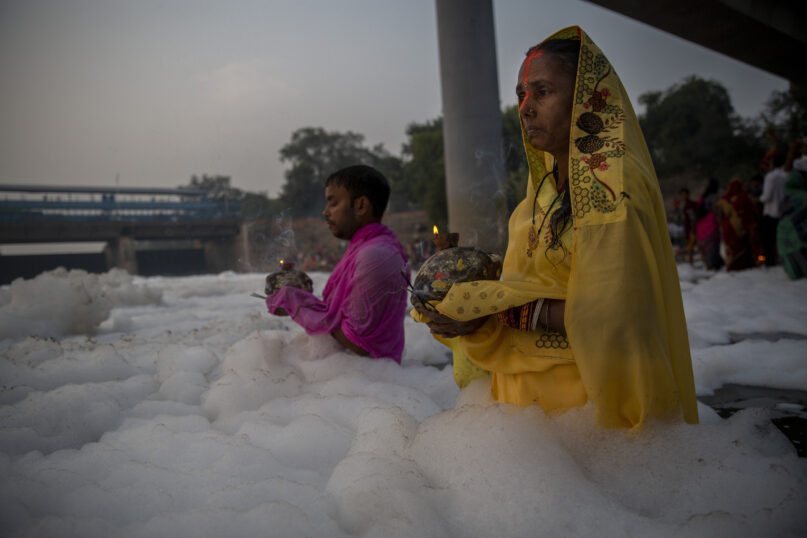 Indian Hindu devotees perform rituals in Yamuna river, covered by chemical foam caused due to industrial and domestic pollution, during Chhath Puja festival in New Delhi, India, Wednesday, Nov. 10, 2021. A vast stretch of one of India's most sacred rivers, the Yamuna, is covered with toxic foam, caused partly by high pollutants discharged from industries ringing the capital New Delhi. Still, hundreds of Hindu devotees Wednesday stood knee-deep in its frothy, toxic waters, sometimes even immersing themselves in the river for a holy dip, to mark the festival of Chhath Puja. (AP Photo/Altaf Qadri)