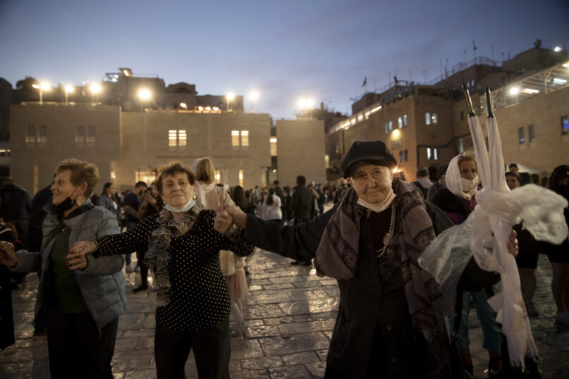 Holocaust survivors dance during a Hanukkah menorah lighting ceremony at the Western Wall, in the Old City of Jerusalem, Tuesday, Nov. 30, 2021. Holocaust survivors marked the third night of Hanukkah on Tuesday with a menorah-lighting ceremony at Jerusalem's Western Wall that paid tribute to them and the 6 million other Jews who were killed by the Nazis. (AP Photo/Maya Alleruzzo)