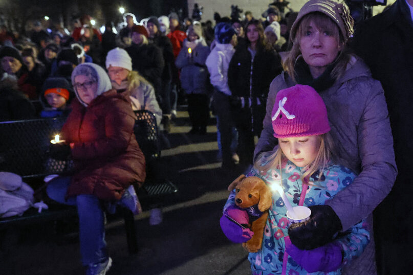 A child takes part in a candle light vigil in downtown Waukesha, Wisconsin, Monday, Nov. 22, 2021, after an SUV plowed into a Sunday Christmas parade killing five people and injuring dozens. (AP Photo/Jeffrey Phelps)
