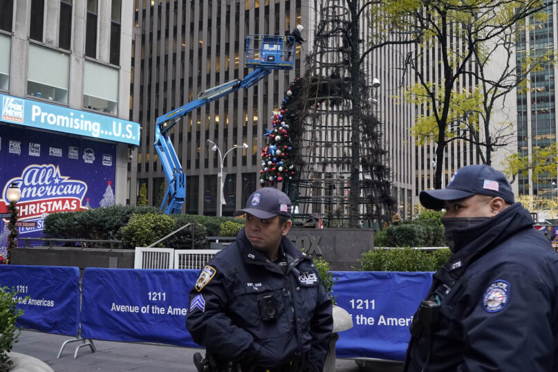 New York City Police stand outside Fox News headquarters as a Christmas tree is disassembled, in New York, Wednesday, Dec. 8, 2021. Police say a man is facing charges including arson for setting fire to a 50-foot Christmas tree in front of Fox News headquarters in midtown Manhattan. The tree outside of the News Corp. building that houses Fox News, The Wall Street Journal and the New York Post caught fire early Wednesday. (AP Photo/Richard Drew)